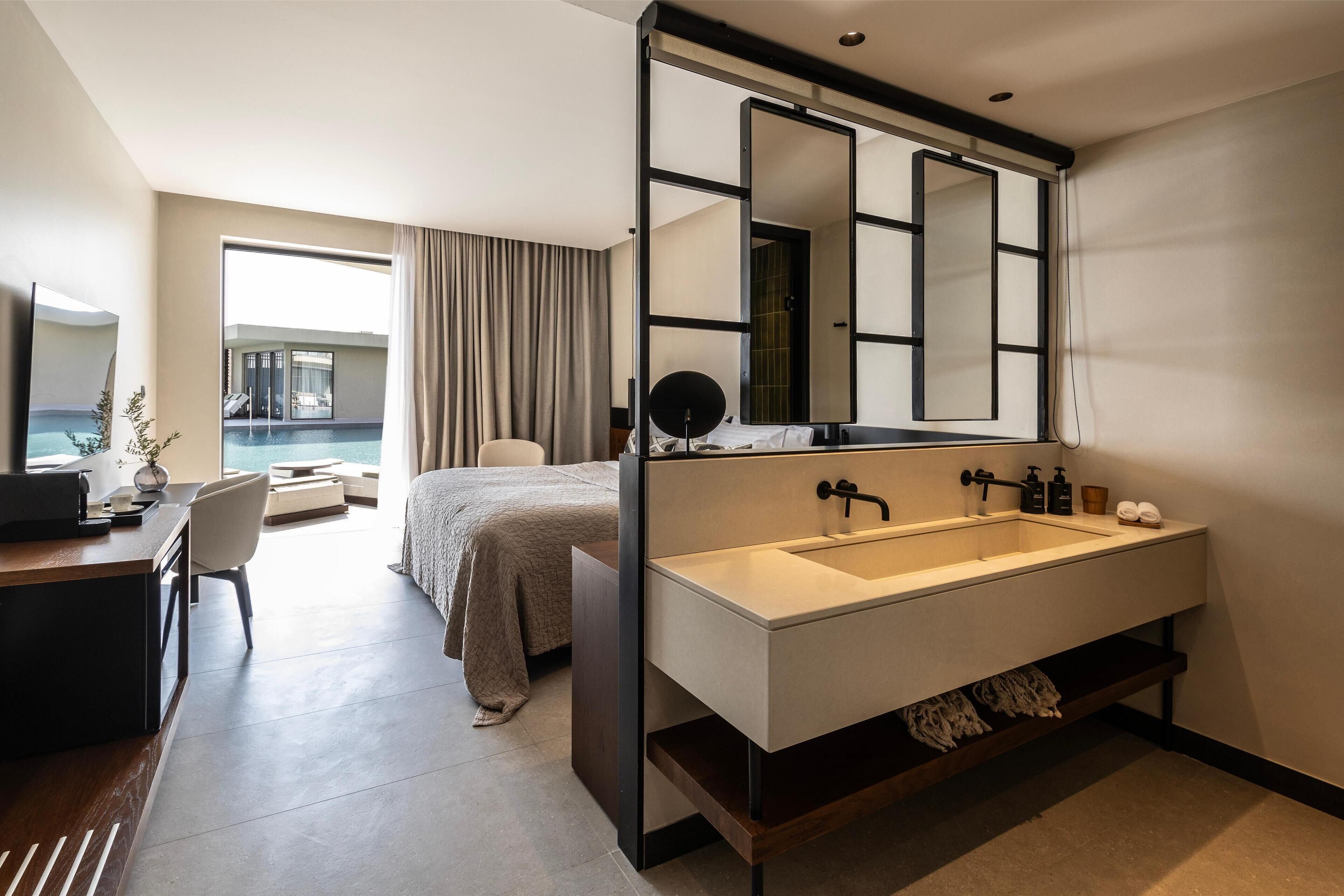 A modern hotel room with a large bathroom, a desk, and a bed.