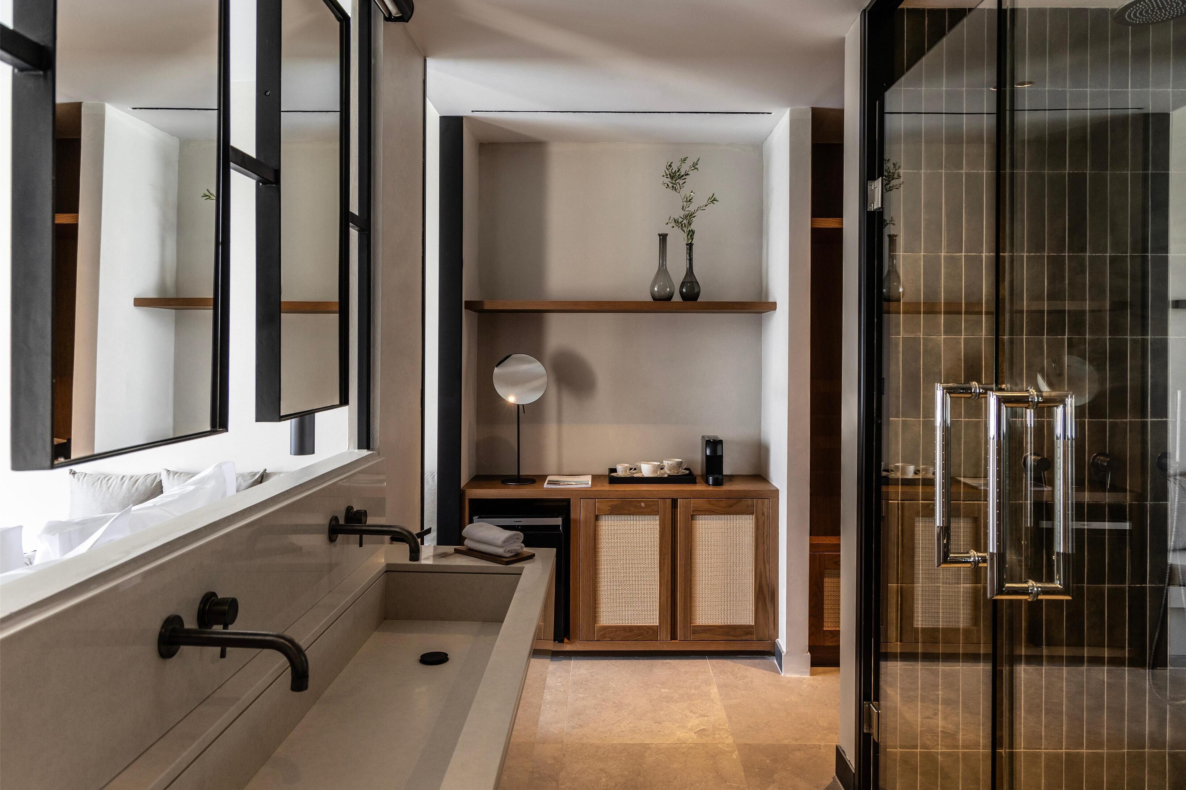 Een moderne badkamer met een grote spiegel, een wastafel, een wastafelmeubel met spiegel en een douchehoek.