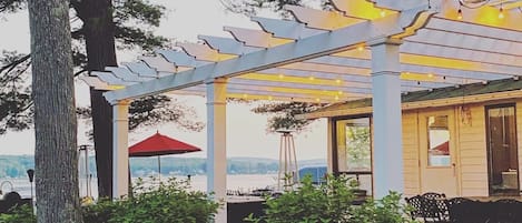 Un espacio de estar al aire libre cubierto con un pérgola, una sombrilla roja y vistas al paisaje.