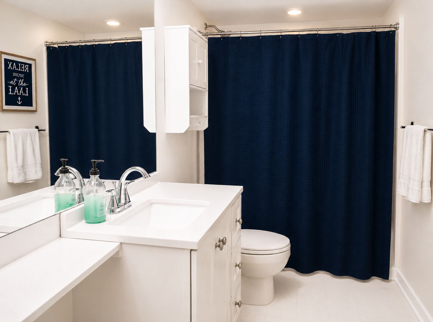 A bathroom with a white sink, a toilet, and a dark blue shower curtain.
