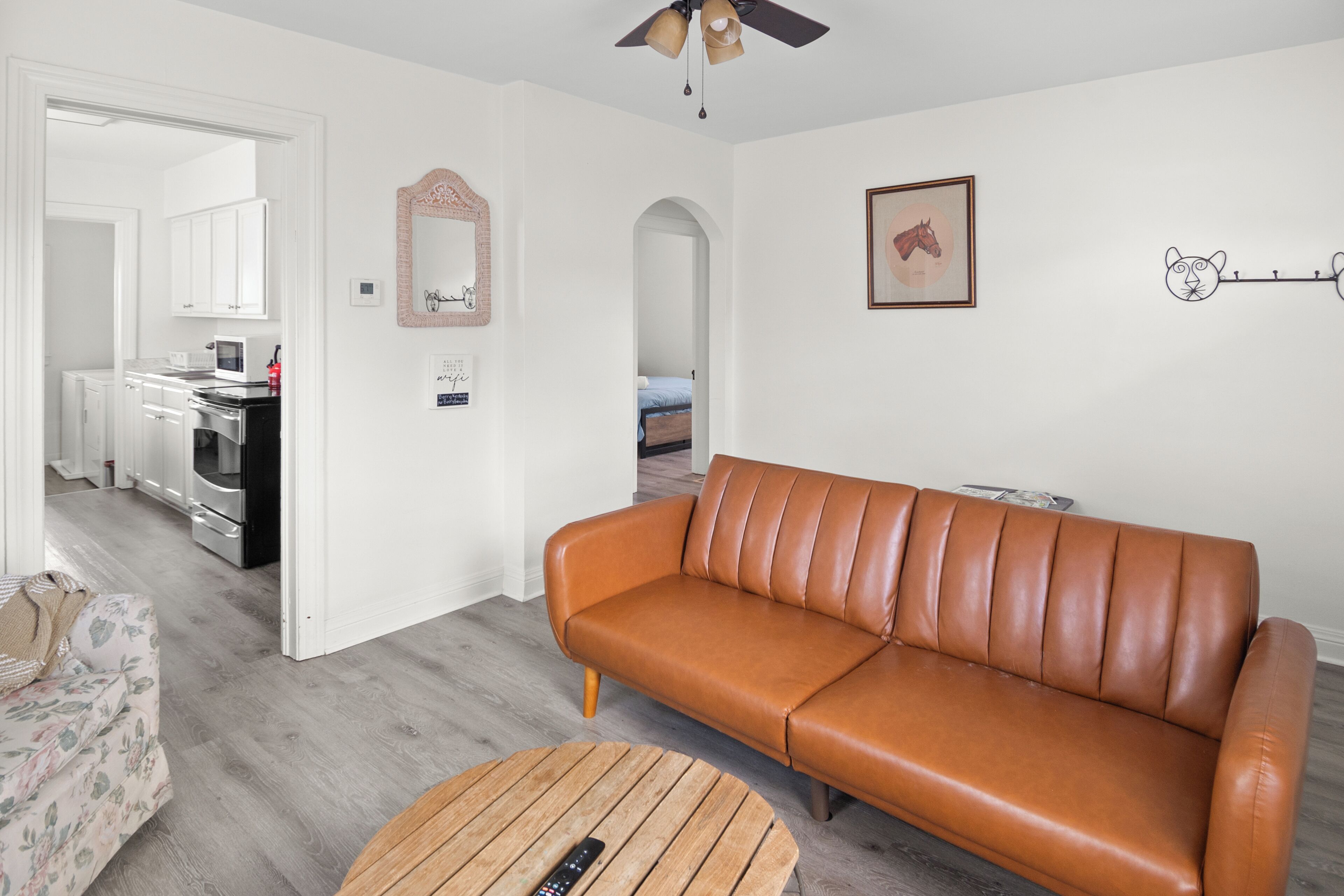A modern living room with a brown leather sofa, a wooden coffee table, and a kitchen in the background.