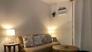 Uma sala de estar aconchegante com um sofá bege, duas mesas laterais com luminárias e uma pequena mesa de madeira.