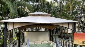 Uma banheira de hidromassagem sob um gazebo com uma placa exibindo as regras do spa.