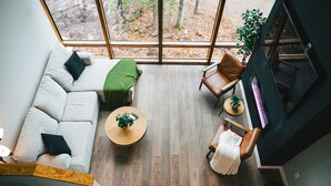 A modern interior with a wooden floor, a sofa, a chair, and a table with a plant. - World famous architect Design + Build (Tofte)