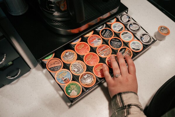 A hand selecting coffee pods from a box on a kitchen counter. - World famous architect Design + Build (Tofte)