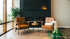 A room with two leather chairs, a small round table, a fireplace, and a large window. - World famous architect Design + Build (Tofte)