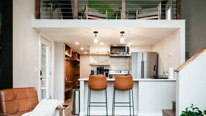 A modern kitchen with a central island, two bar stools, and a dining area. - World famous architect Design + Build (Tofte)