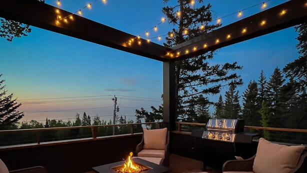 An outdoor patio area with string lights, a fire pit, and outdoor furniture. - World famous architect Design + Build (Tofte)