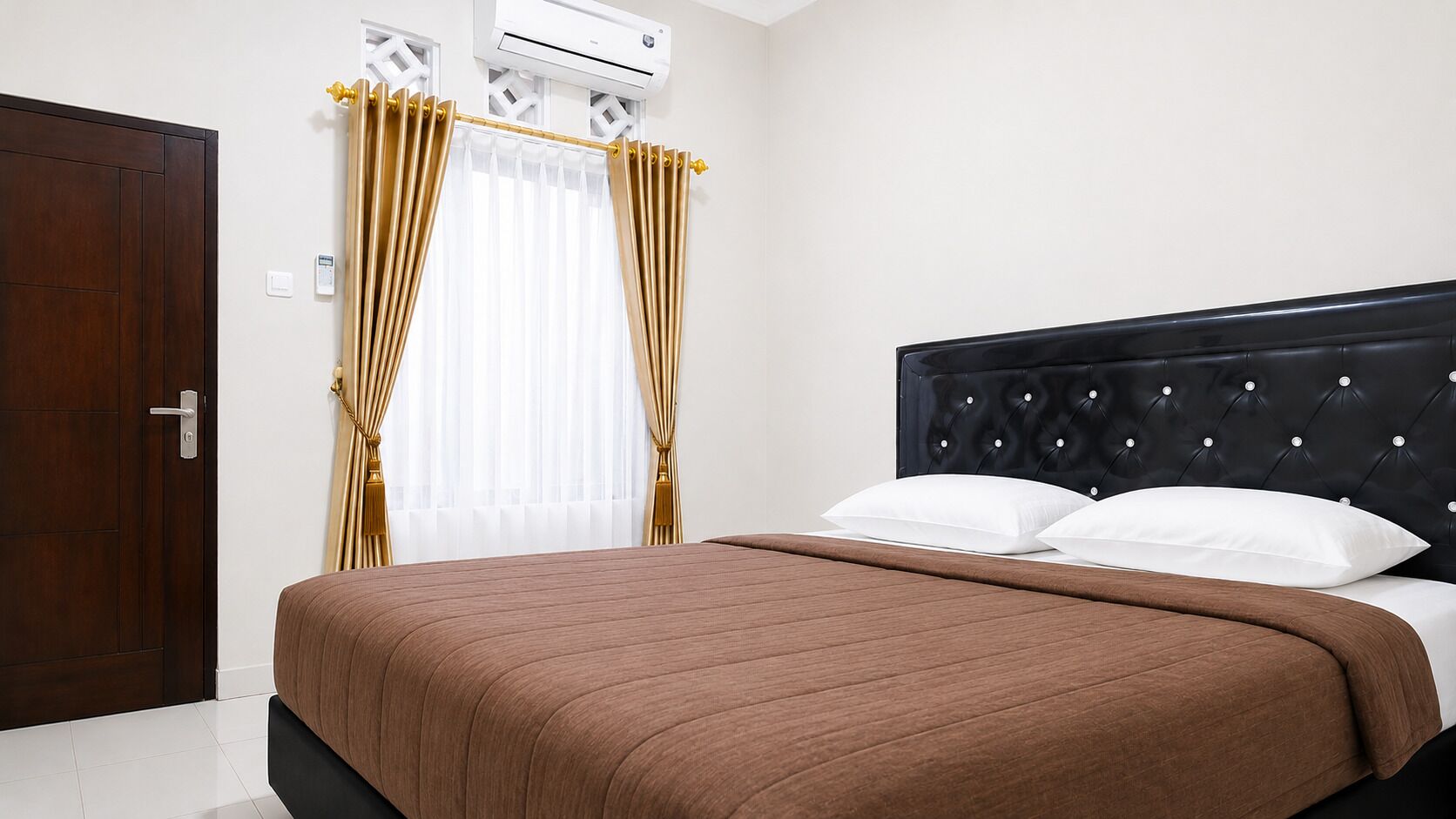 A hotel room with a bed, curtains, an air conditioning unit, and a door.