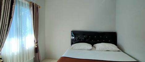 Ein Schlafzimmer mit einem Bett, Vorhängen und einer Klimaanlage.
