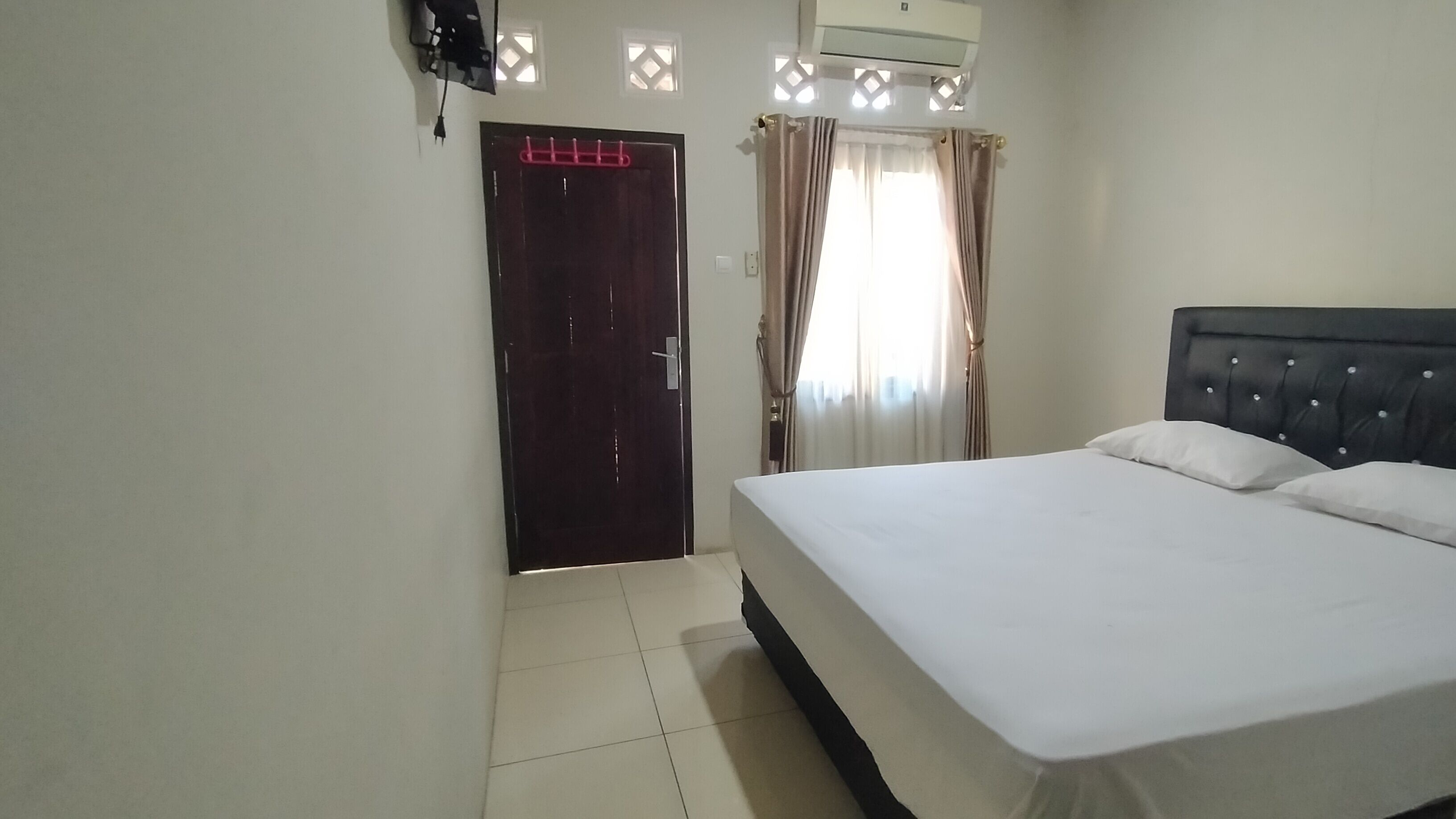A bedroom with a bed, a door, and a window with curtains.