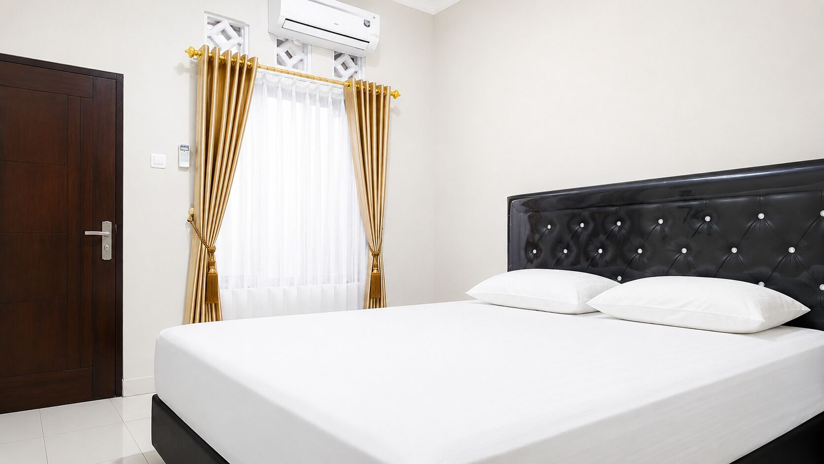 A hotel room with a bed, curtains, an air conditioning unit, and a door.