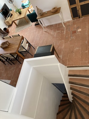 Ein modernes Interieur mit einem Holzesstisch, Stühlen, einer Treppe mit Holzbeschlägen und einer weißen Wand.
