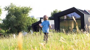 A child playing in a field with a modern building in the background. - Tiny House Nr.1 - Wird Noch Bearbeitet - Provisorisch Erstellt (Bad Wurzach)