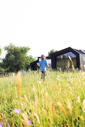 Niño jugando en un campo con un edificio moderno al fondo.