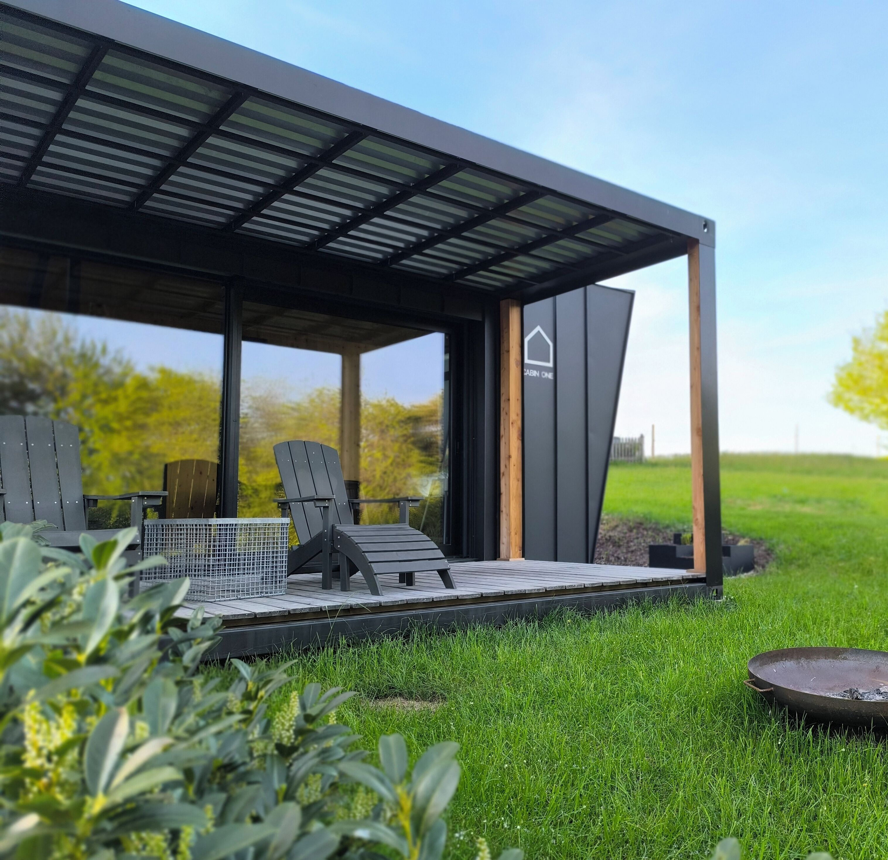 Un espace extérieur moderne, aménagé avec un patio couvert, un barbecue en métal et un panneau indiquant la présence d’un chalet.