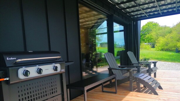 An outdoor patio with a grill, two chairs, and a table. - Tiny House Nr.1 - Wird Noch Bearbeitet - Provisorisch Erstellt (Bad Wurzach)
