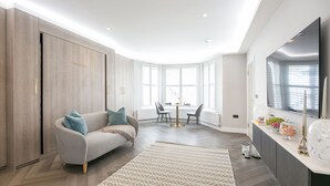 A modern living room with a sofa, a coffee table, and a dining area with chairs.