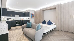 A modern apartment with a kitchen, a sofa, and a bed.