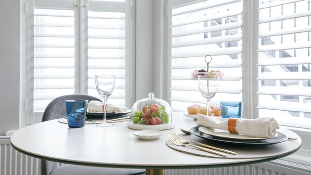 A dining table set with plates, cutlery, and a glass bowl with grapes.