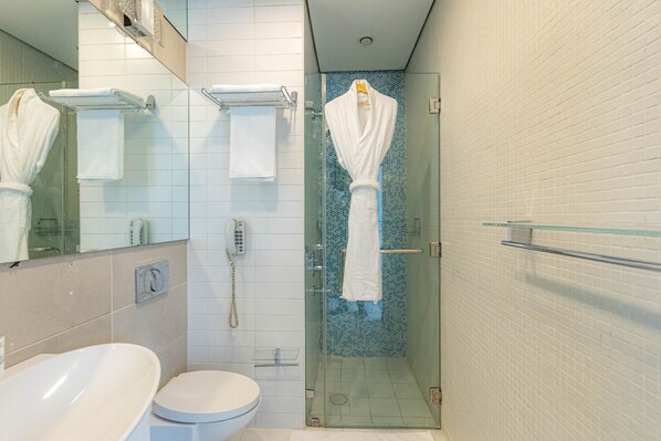 Un baño moderno con ducha de vidrio, inodoro blanco y un espejo grande.