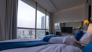 A hotel room with two beds, a television, and a view of the cityscape. - Boho Boutique Hotel (Amman)