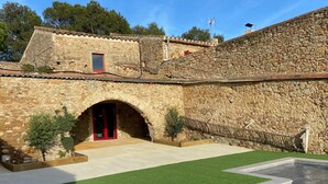 A stone building with a swimming pool, a red door, and a small window. - Torre Bertrana by Duquessa Hotel Collection (Pals)