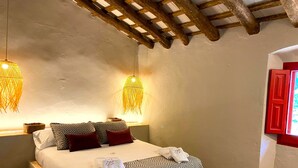 A hotel room with a bed, two hanging lamps, a red door, and a window. - Torre Bertrana by Duquessa Hotel Collection (Pals)