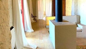 A corridor with white walls and a tiled floor, leading to a seating area with a sofa and a small table. - Torre Bertrana by Duquessa Hotel Collection (Pals)