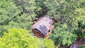 Eine Holzhütte, umgeben von dichtem Wald, mit geneigtem Dach und Holzfassade.