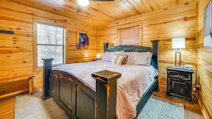 Ein Schlafzimmer einer Holzhütte mit einem Bett, einem Nachttisch und einem Deckenventilator.