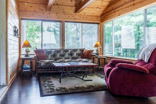 Four-season room at golden hour, warm light, comfortable seating, and the sounds of Paradise just outside the windows