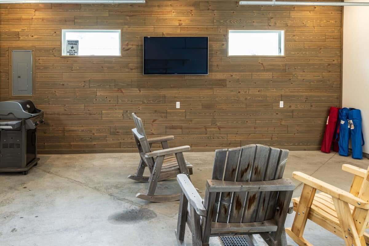 A garage with wooden walls, a mounted television, and a concrete floor.