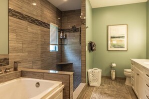 Une salle de bain moderne dotée d’une grande baignoire, d’un espace douche et de toilettes.