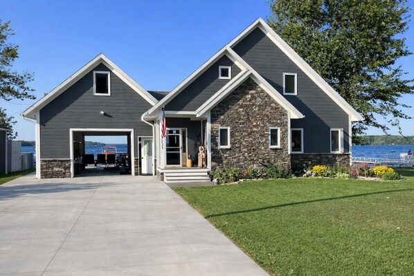 Une maison à deux étages avec une façade en pierre, un garage et une vue sur un lac.