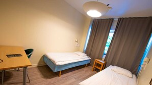 A small, well-lit room with two beds, a desk, and a chair. - Kvarntorgets Vandrarhem (Uppsala)
