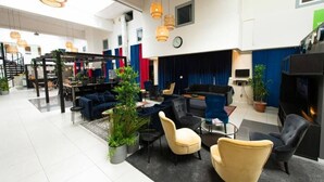 A spacious lobby with a seating area, a staircase, and a large screen. - Kvarntorgets Vandrarhem (Uppsala)