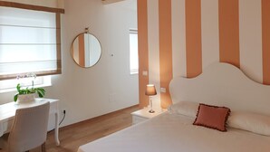 Una camera da letto con un letto, un comodino, una lampada e una scrivania con sedia e pianta.
