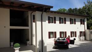 Un edificio a due piani con vialetto e un'auto decappottabile parcheggiata.