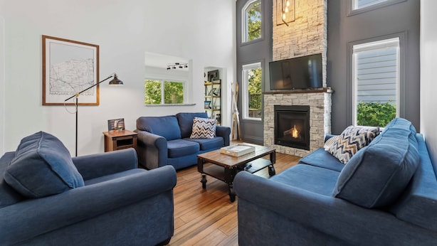A modern living room with a fireplace, blue sofas, a coffee table, and a map on the wall. - Château Ravine, backing onto a beautiful tree-filled ravine  (Niagara-on-the-Lake)