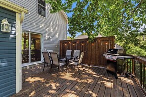 A deck with a grill, chairs, and a table.