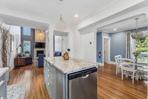 Una cocina moderna con lavavajillas, un comedor con mesa y sillas, y una sala de estar con sofá y chimenea.