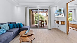 A modern living room with a grey sofa, a wooden coffee table, and a dining area with a table and chairs. - Gav5: New Modern Condo Walking Distance to Beach (Tamarindo)