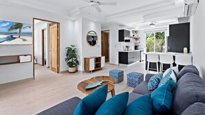 A modern living room with a sofa, coffee table, and a view of the beach. - Gav5: New Modern Condo Walking Distance to Beach (Tamarindo)