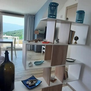 A modern living room with a large window, a dining area, and a view of the outdoors.