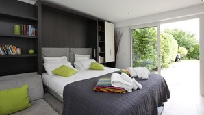 Una camera da letto moderna con un letto grande, una libreria a muro e una porta scorrevole in vetro che dà su un balcone.