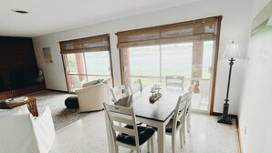 Un salón amplio con comedor, ventanas grandes y vista a un cuerpo de agua.