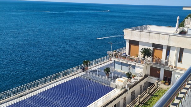 Ein Hochhaus mit Dachterrasse, Solaranlage, Balkon und Blick auf das Meer.