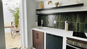 A modern kitchen with a built-in dishwasher, a sink, and a stove. There is a window providing natural light and a view of an outdoor seating area. - Art Oasis 2-3BR Home in Historic Quarter by Portimao Pier (Portimão)