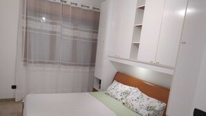 Ein Schlafzimmer mit Bett, Kleiderschrank und Regalelement.